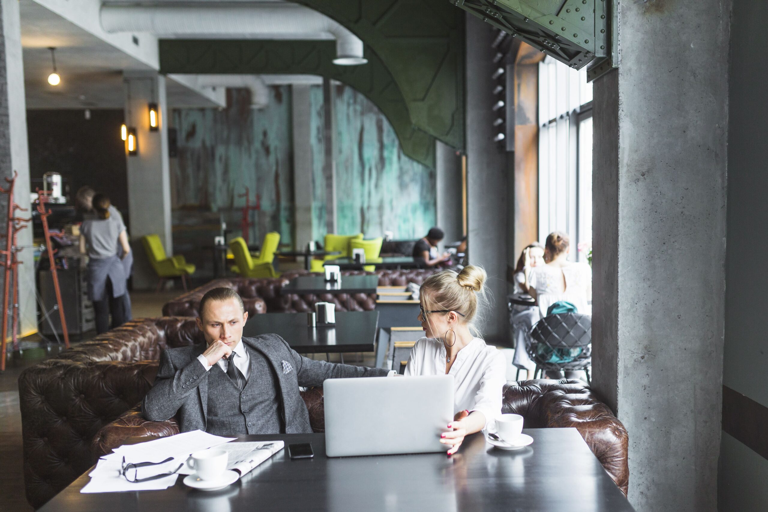 two business people with laptop sitting restaurant discussing Merchant Cash Advances