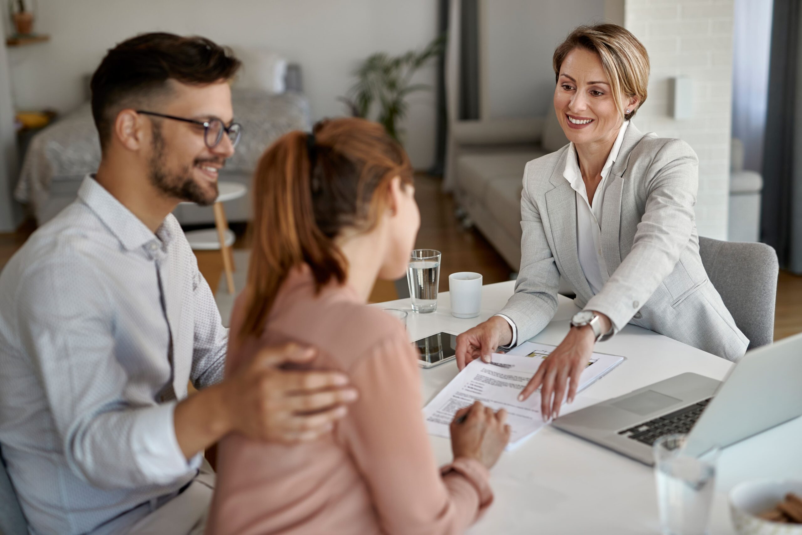 happy real estate agent having meeting with young couple pointing place signature their contract