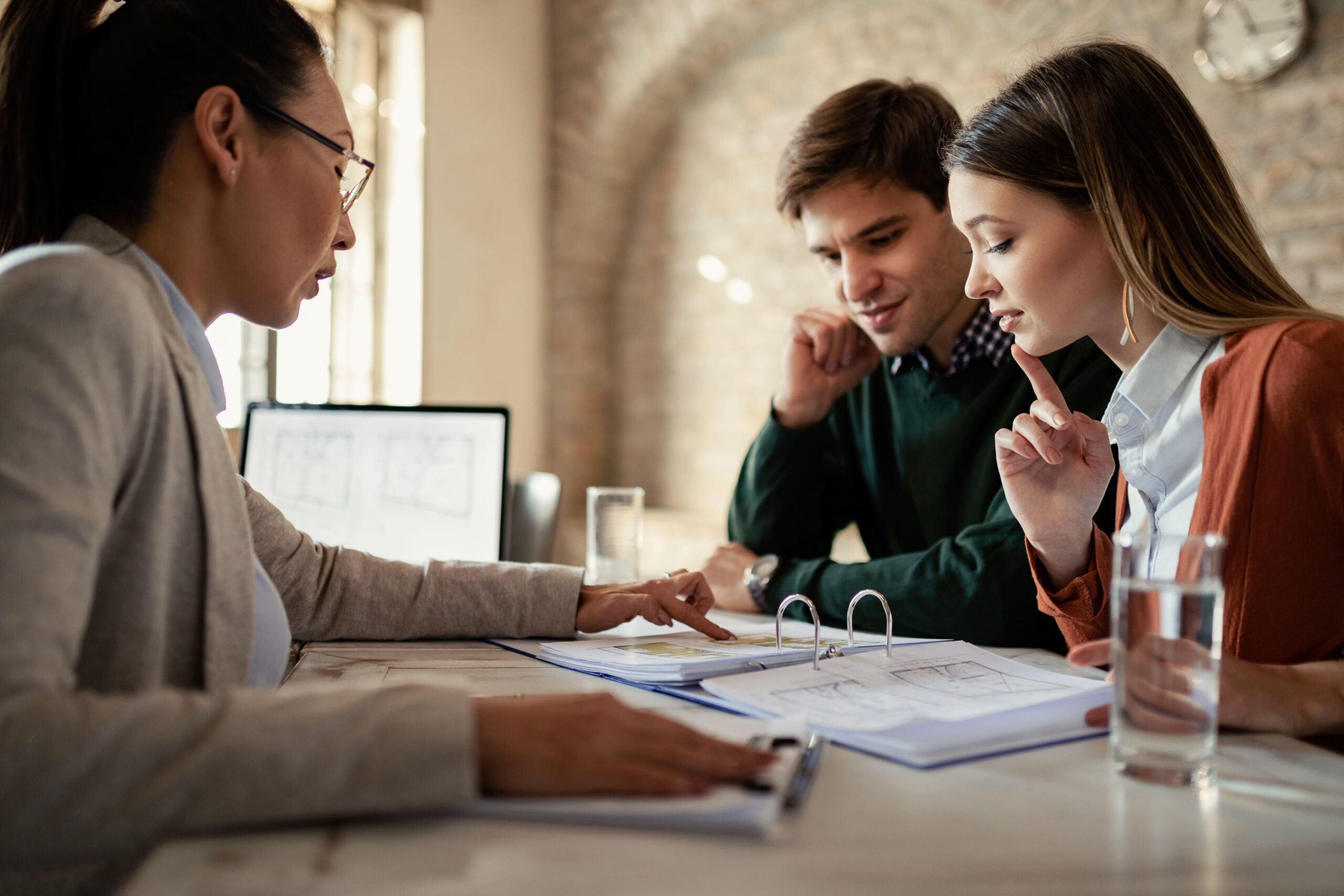 young man his wife examining housing plans with real estate agent meeting office